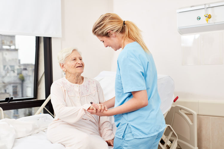 Nurse holding hands of senior female patient at hospital
