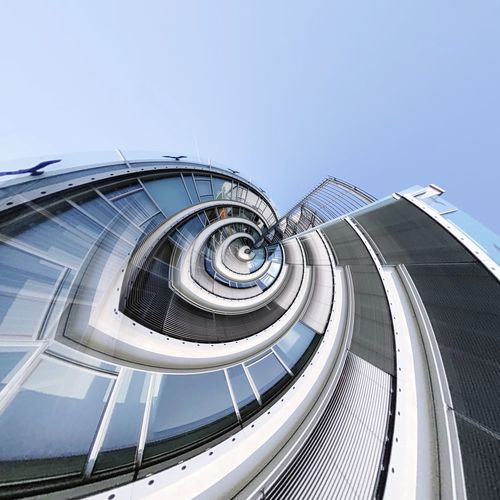 Fish-eye view of modern building against blue sky