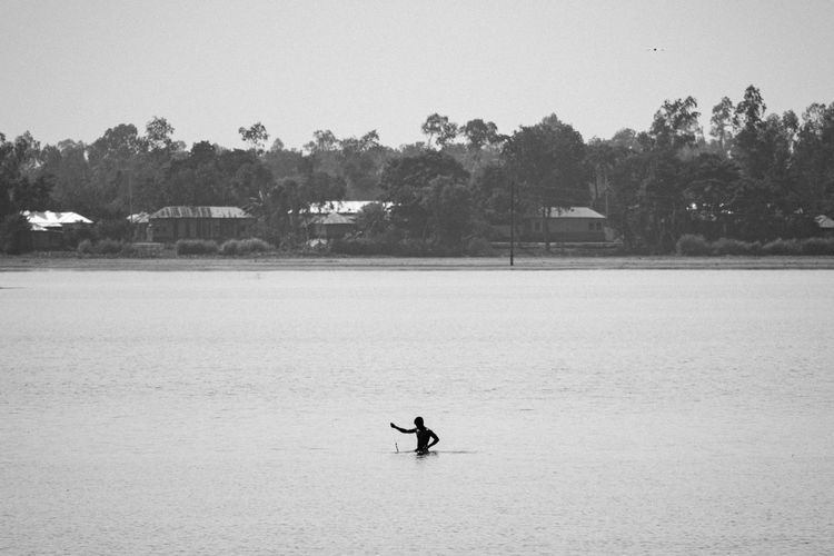 Man surfing on riverbank against sky