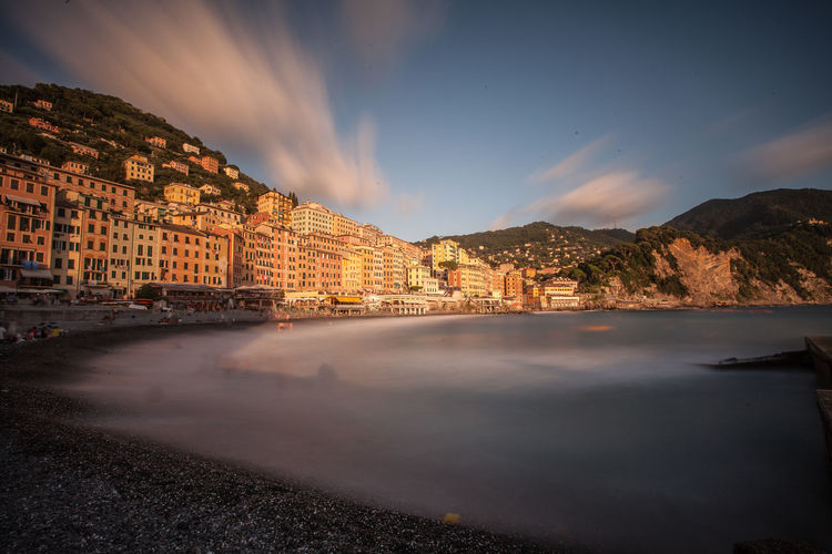 Buildings in camogli at sea shore against sky during sunset