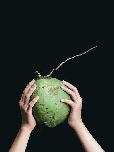 Cropped hand holding apple against black background