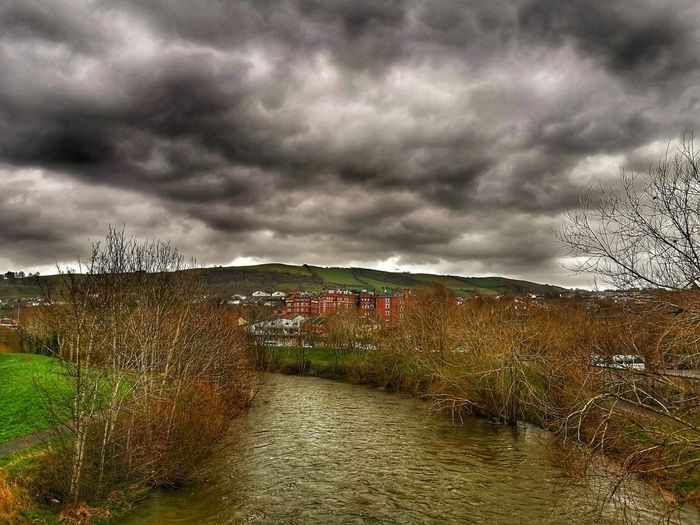 Scenic view of river against cloudy sky