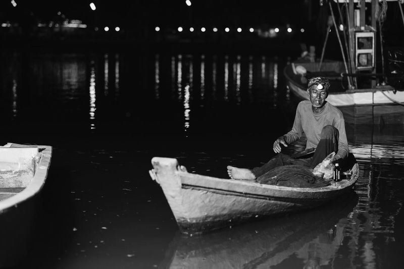 Man sitting on boat in river at night