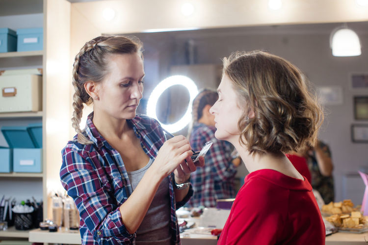 Make-up artist applying make-up to model at studio