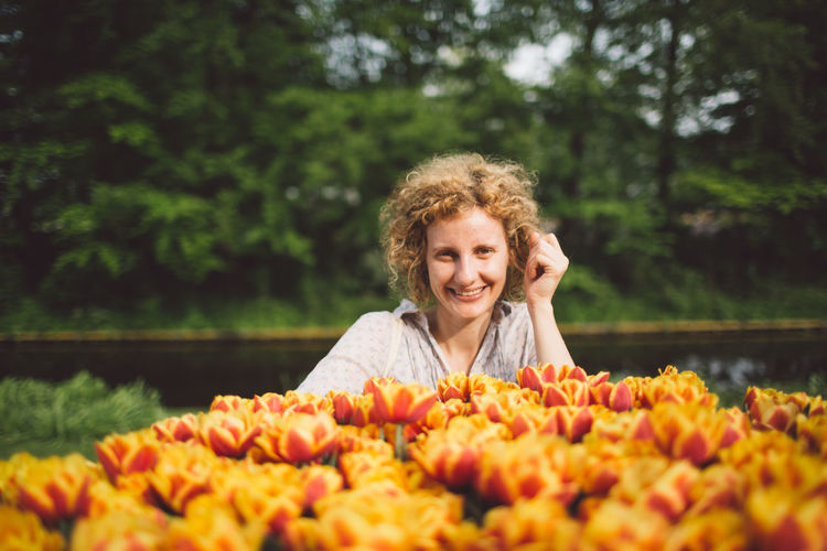 Portrait of smiling woman with orange tulips blooming at park