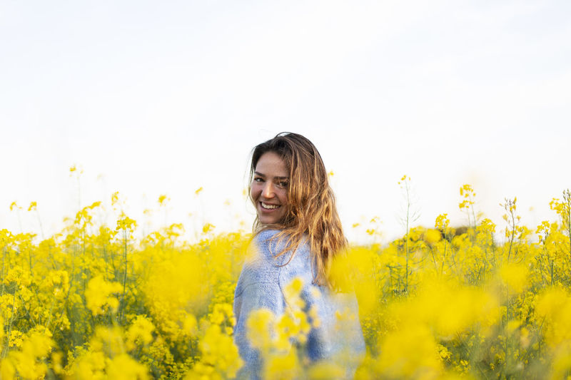 Portrait of smiling young woman with yellow flowers in field