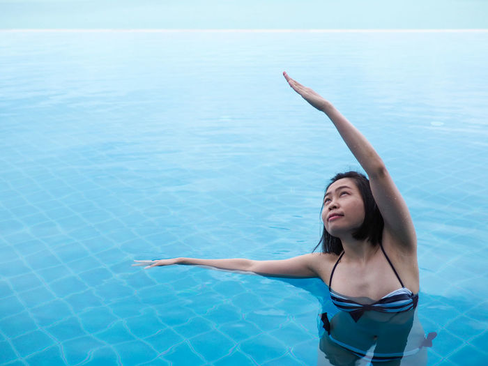 Young woman in bikini standing by swimming pool