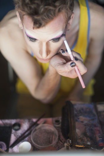 Man looking in mirror and putting on drag cosmetics