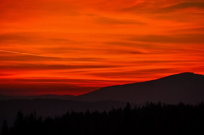 Scenic view of silhouette mountains against orange sky