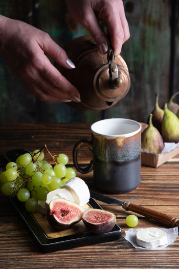 Cheese plate with goat cheese, grapes and figs, copper teapot, angle view