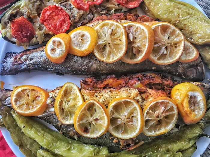 Close-up of fish with lemon and tomato slices in plate