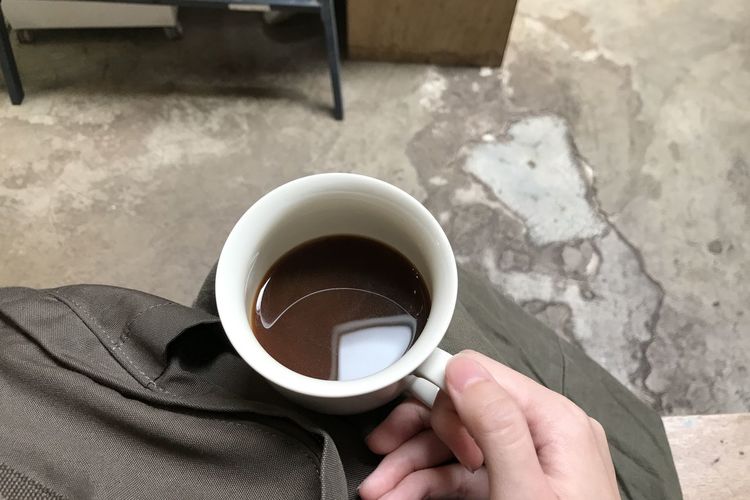 High angle view of hand holding coffee cup