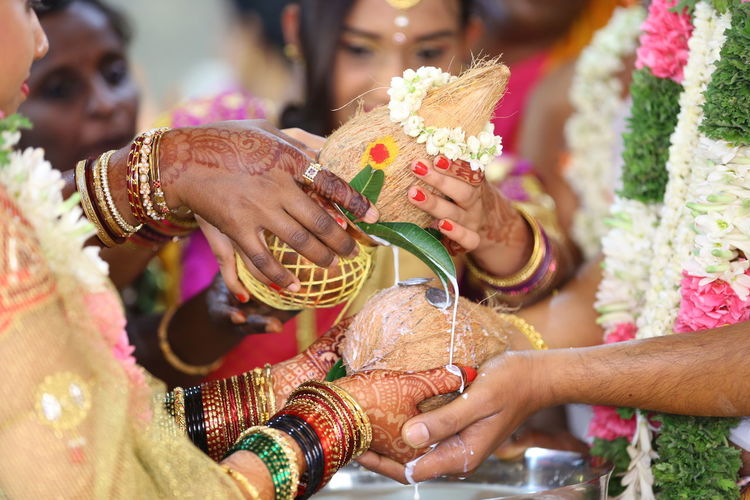 Bride and groom holding coconut during weeding rituals