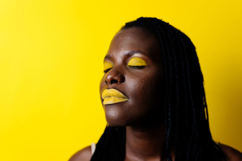 Close-up of woman against yellow background
