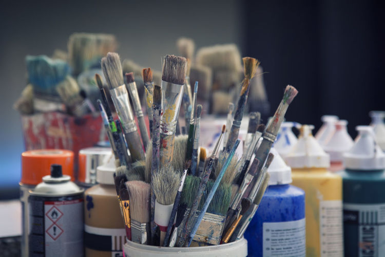 Close-up of paintbrushes by paint bottles