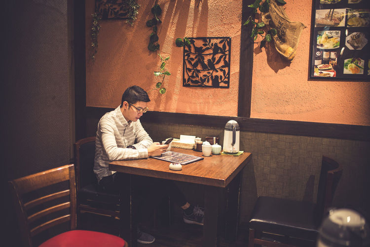 Man using mobile phone while sitting in restaurant at night