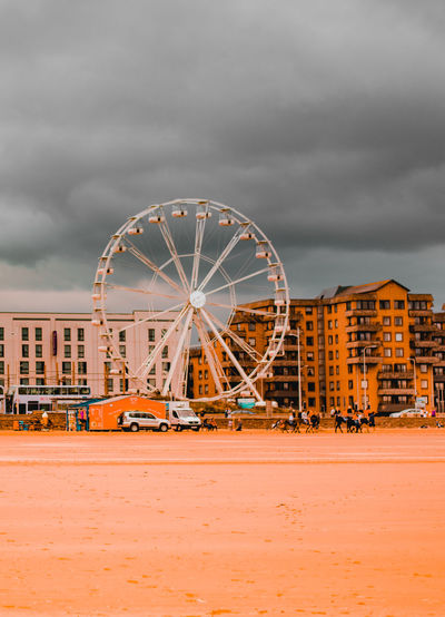 Ferris wheel in amusement park against cloudy sky