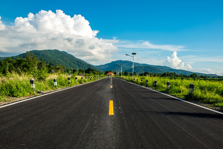 Road amidst green landscape against sky
