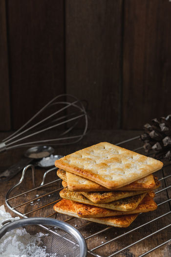 Square dry crackers biscuit on a wooden table. wooden texture dark background. snack dry biscuits