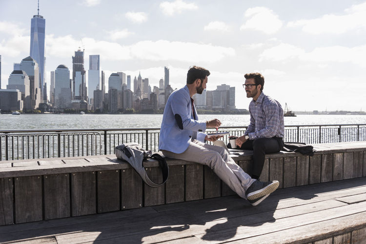 Usa, two businessmen working at new jersey waterfront with view to manhattan