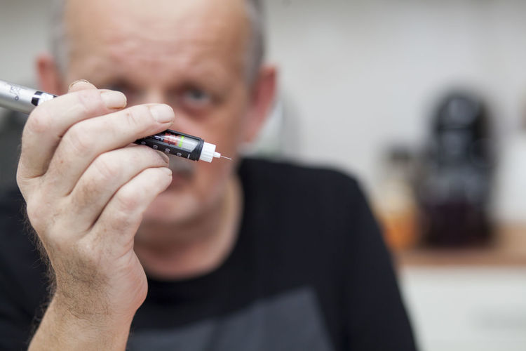 Close-up of mature man holding insulin equipment
