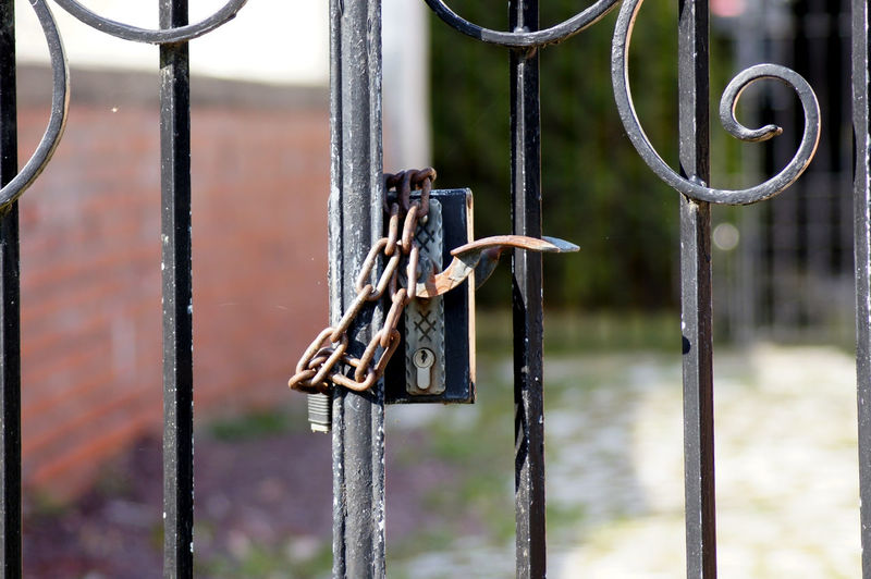 Close-up of rusty chain hanging on metal gate