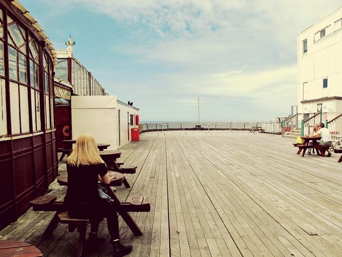 People sitting at table on north pier against cloudy sky