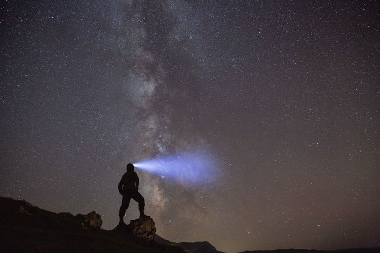 Silhouette man standing against star field at night