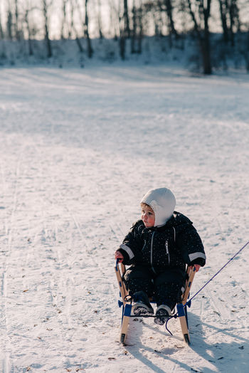 Toddler sitting on sleigh on snow covered field