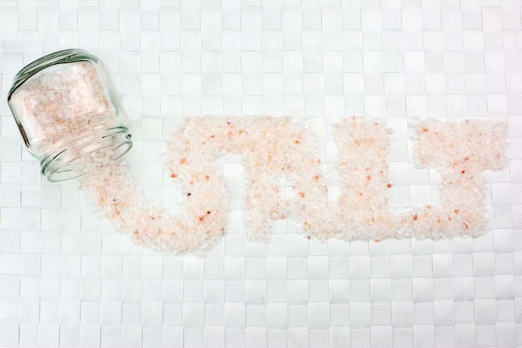Open vase and word  salt written with pink salt on white background