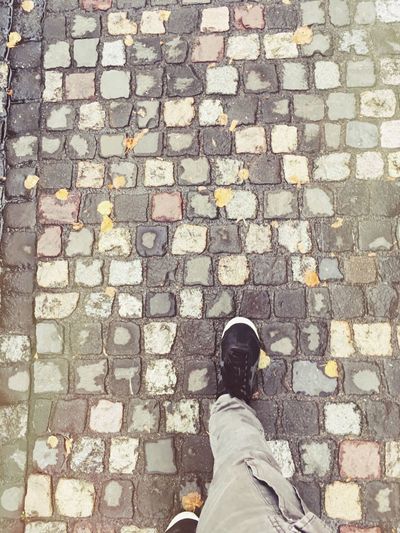 Low section of man standing on cobblestone street