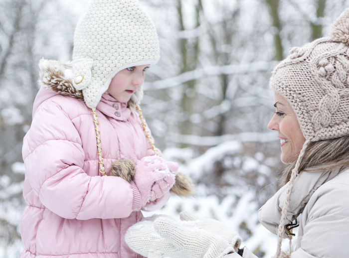 Mother and daughter playing with snowball during winter