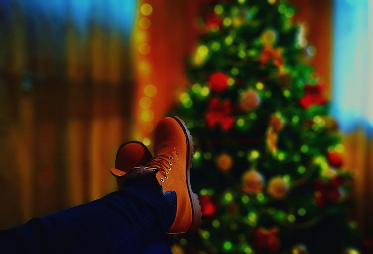 Low section of person wearing shoes against christmas tree