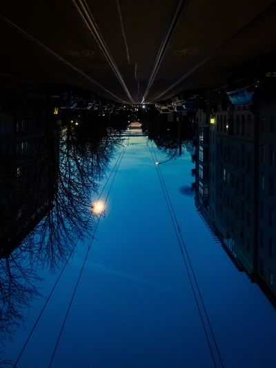 Illuminated bridge against blue sky at night