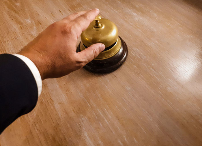 High angle view of human hand ringing bell on reception desk