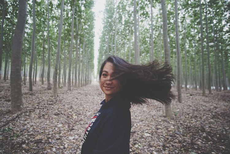 Portrait of young woman tossing hair in forest