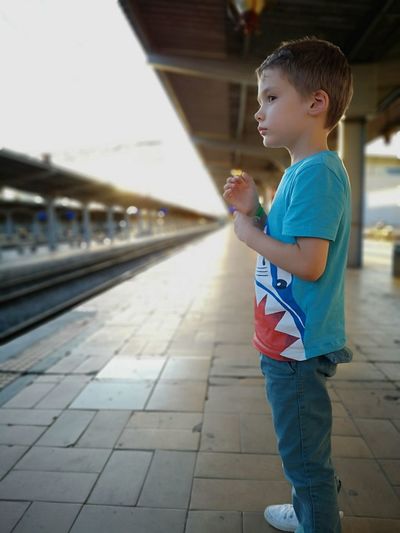 Profile view of boy standing at railroad station platform