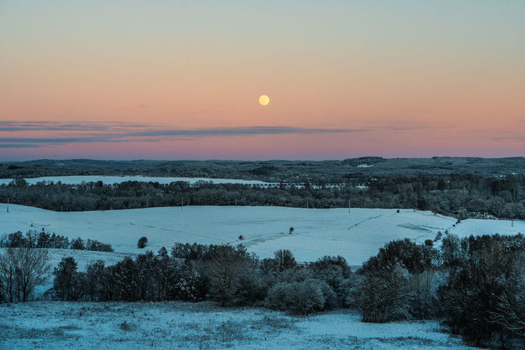 Scenic view of snow covered landscape against sky during sunset