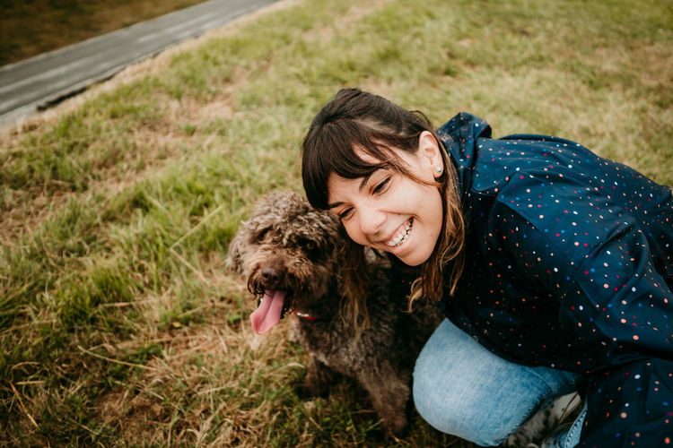 Smiling woman with dog on field