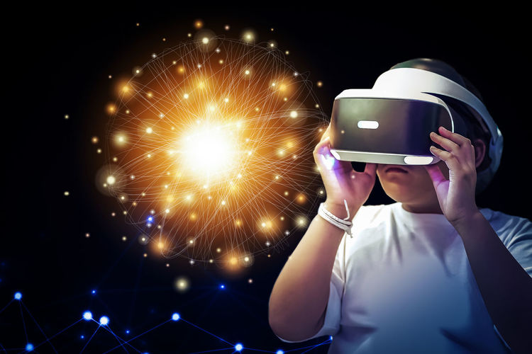 Girl wearing virtual reality simulator against black background