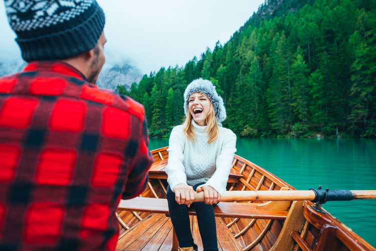 Smiling woman with man sitting in rowboat at lake