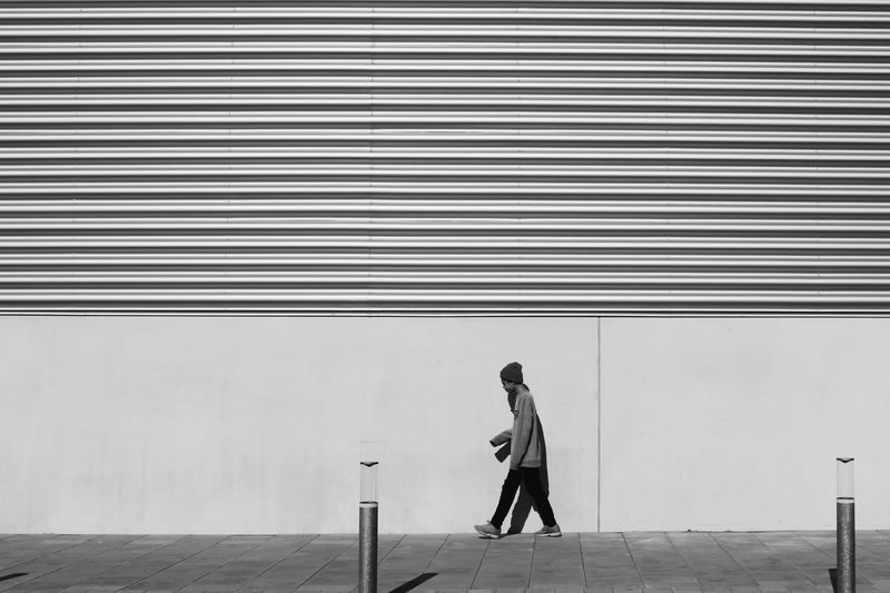 Teenage boy walking on sidewalk against wall