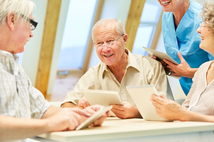 Senior people using digital tablets at table in nursing home