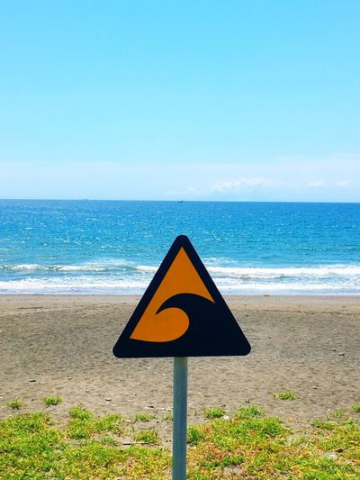 Wave hazard warning sign at beach with sea in background
