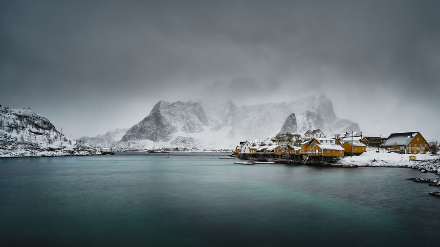 Village by sea against sky during winter