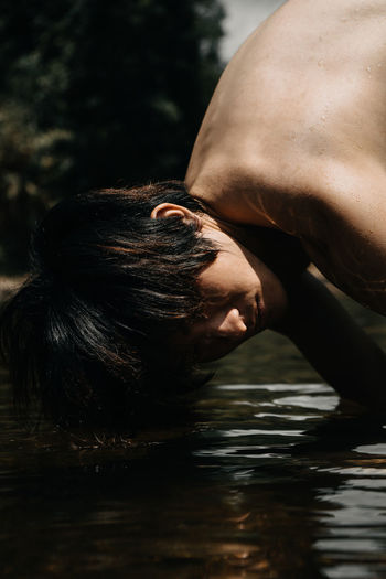 Midsection of shirtless woman in water