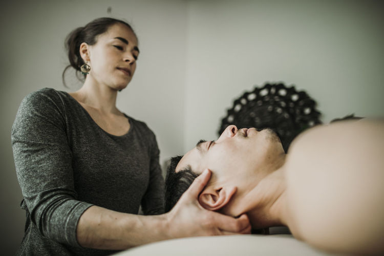 Male massage patient has neck worked on by female massage therapist