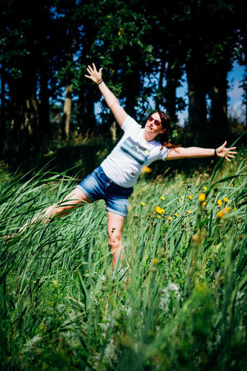 Young woman with arms outstretched standing on grassy field