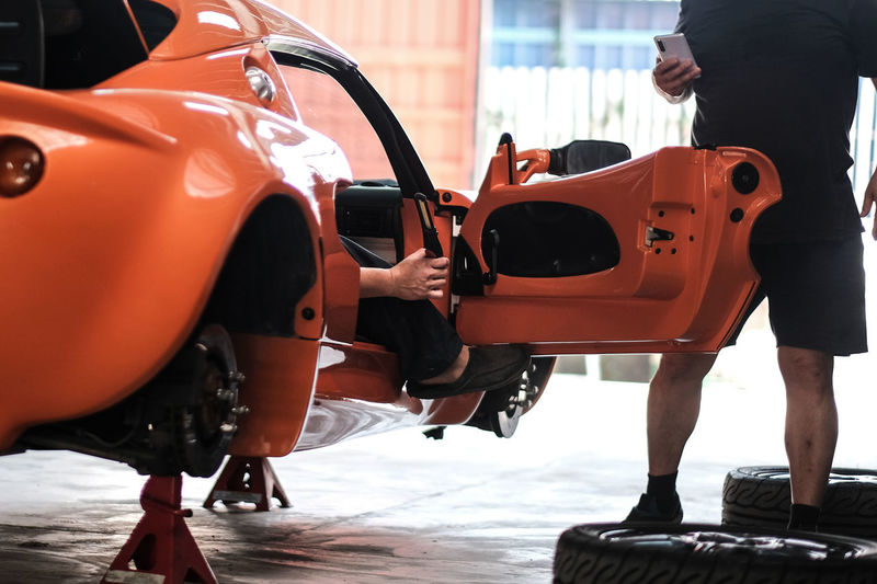 An orange classic sports car in a workshop for inspection