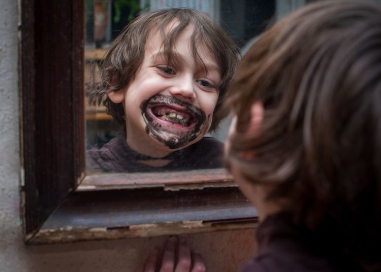 Portrait of happy boy enjoying his reflection in a mirror